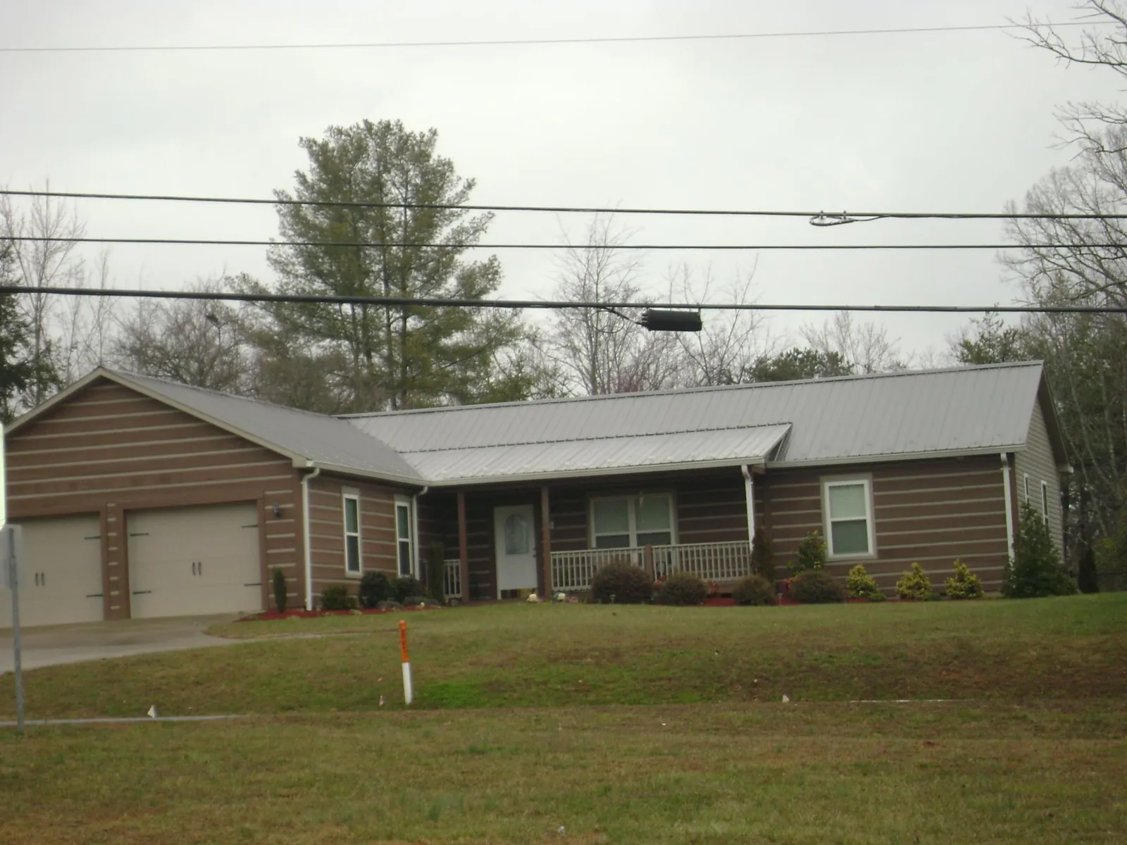 Gray metal roof on a log sided ranch home with a front porch in Kensington