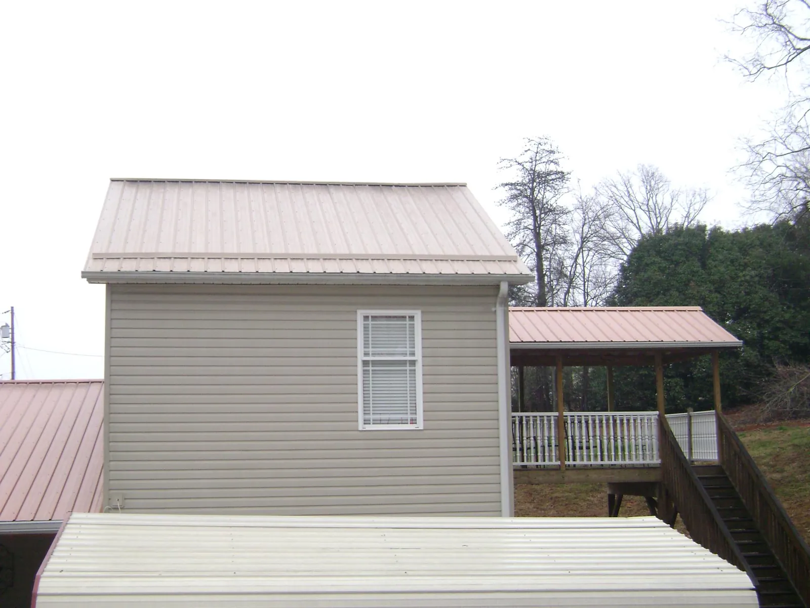 Tan metal roofs on a two story addition and attached porch, from a Roof Replacement job in Kensington